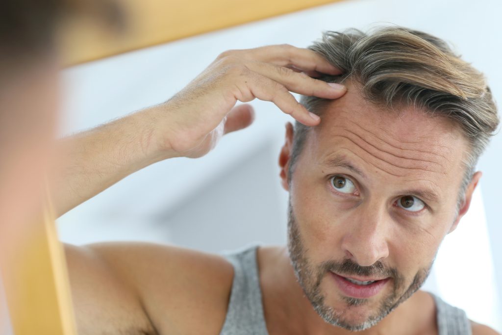 man looking at his hair in the mirror