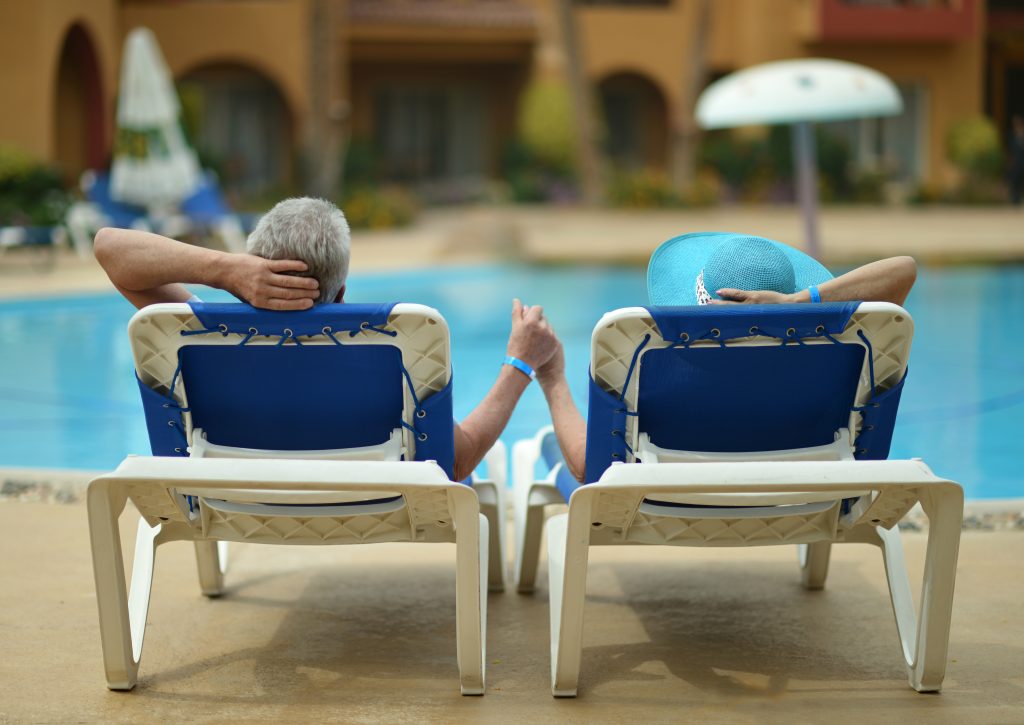 older middle aged couple sitting in chairs by pool