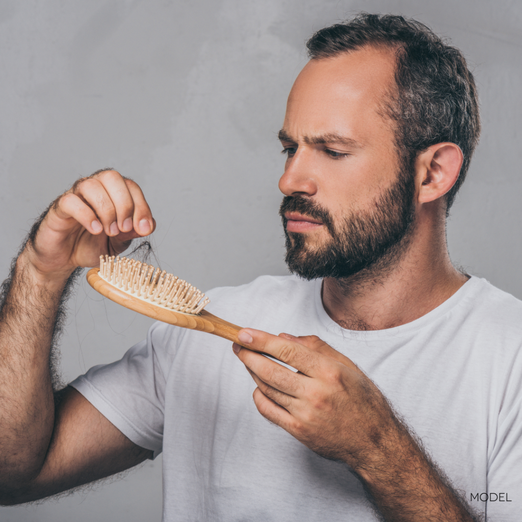 man looking at hair in brush