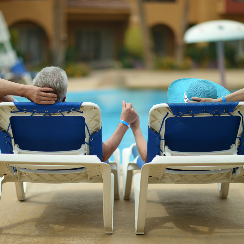 older middle aged couple sitting in chairs by pool