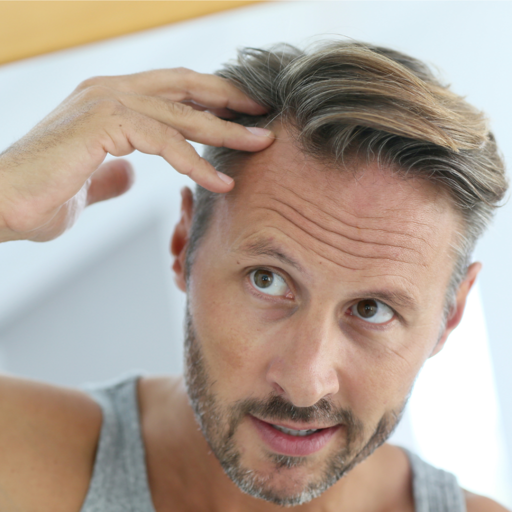 man looking at his hair in the mirror