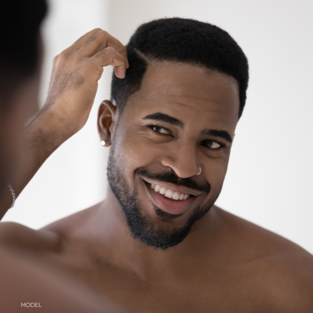 African American man looking in mirror and touching hair