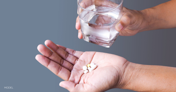 hands holding a glass of water and medication