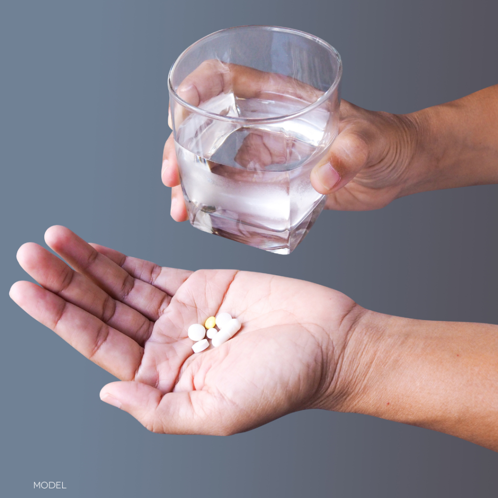 hands holding a glass of water and medication