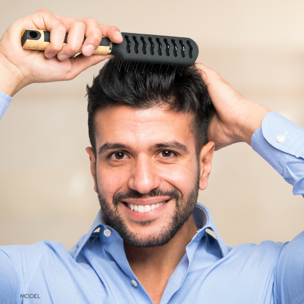 man brushing his hair and smiling at the camera