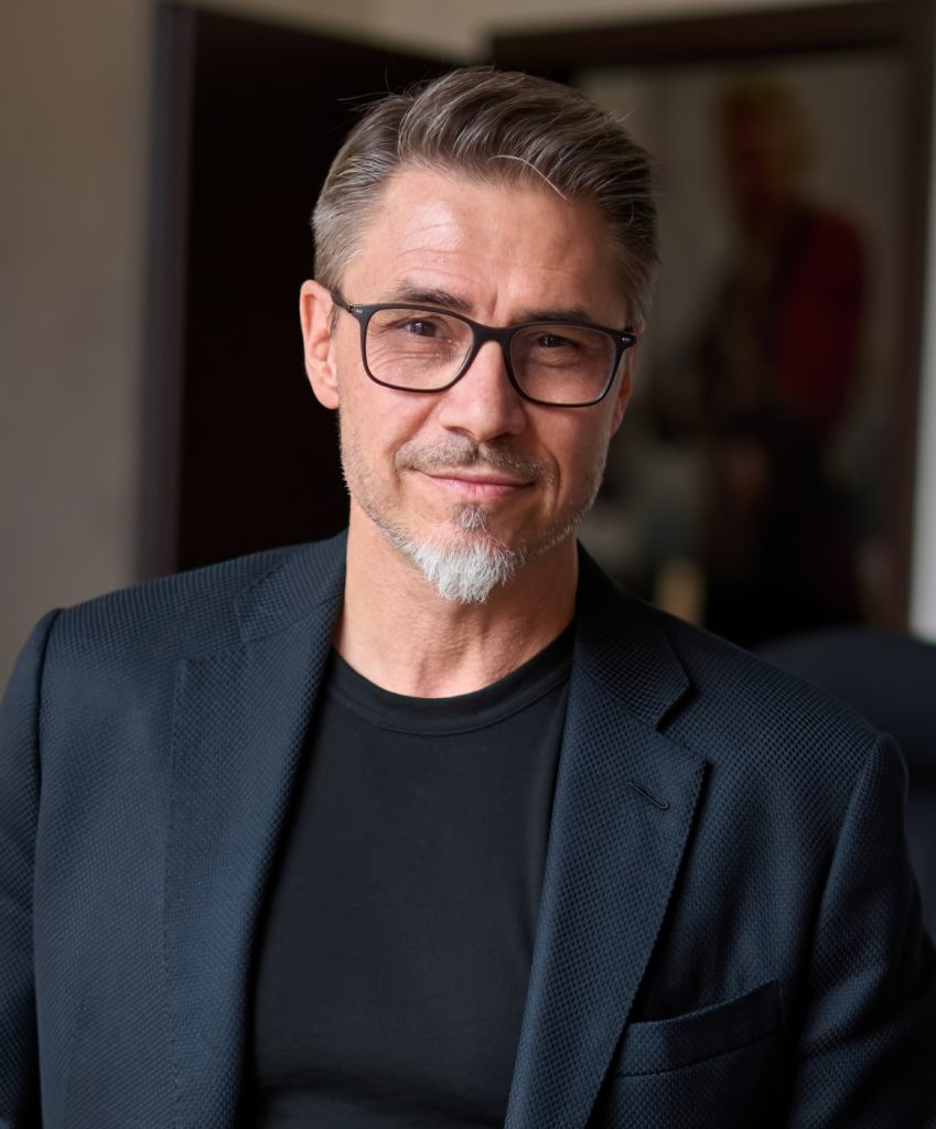 Middle aged man with glasses smiling while wearing a nice suit jacket