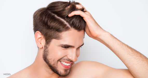 Young man with hand through hair, smiling