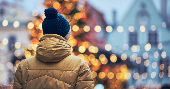 back of man, looking at holiday lights, bundled up in coat and hat