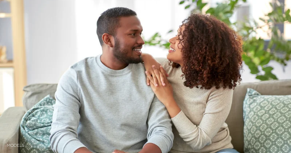 Happy couple sitting on the couch smiling at each other